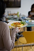 Woman carrying plate of seafood lasagne