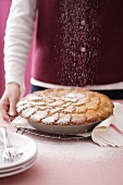 Woman dusting apple pie with icing sugar
