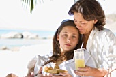 Mother and daughter with a snack on the beach