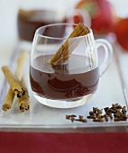 Mulled wine in a glass cup with cinnamon sticks and cloves