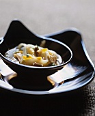 Noodle soup with duck breast and orange peel in glass bowl