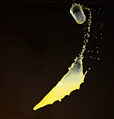 Orangensaft spritzt aus einem fliegendem Glas