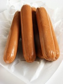 Five hot dog sausages on paper