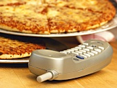 A Cordless Phone Next to Two Pizzas
