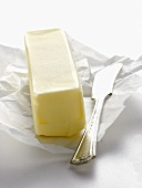 Stück Butter auf Einwickelpapier mit Buttermesser