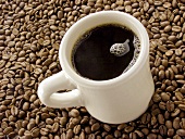 Mug of Black Coffee Resting on Coffee Beans