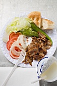 Döner kebab with vegetables on paper plate, drinking yoghurt