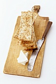 Stacked crackers and cheese with knife on chopping board