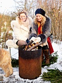 Two woman at a bonfire in a wintry garden