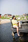 A woman reading a book on a jetty in the sea