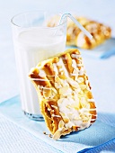 Bärentatzen (madeline-style cakes) with icing sugar and slivered almonds and a glass of milk