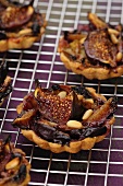 Fig and plum tartlets with pine nuts on a wire rack