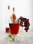 Rotweinglas, rote Trauben und Rotweinflaschen