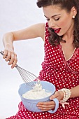 A retro-style girl whipping cream with a whisk