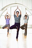 Three women practising yoga in a workout room