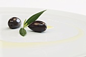Kalamata olives with leaves and olive oil on a plate