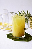 Glass Pitcher of Mint Pineapple Juice on Pineapple Leaf; Glasses
