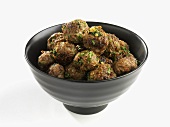 A bowl of meatballs with herbs