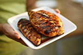 Woman Holding a Platter with Three Grilled Chicken Breasts