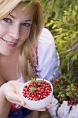 A woman holding a bowl of lingonberries