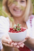 A woman holding a bowl of lingonberries