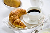 A cup of coffee and a croissant