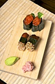 Sushi with mackerel and salmon caviar on a wooden board