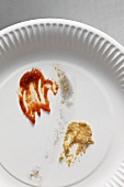 Left over ketchup and mustard on a paper plate
