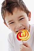 A little boy biting into a lolly