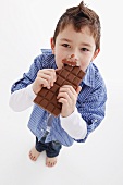 A little boy eating a bar of chocolate