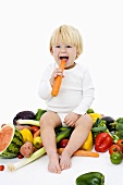 Little child sitting on a pile of vegetables