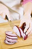 Woman Slicing Red Onion on Cutting Board