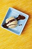 A scoop of vanilla ice cream with chocolate sauce