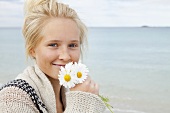 Teenage holding a bunch of daisies at the beach