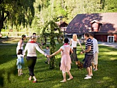 Men, women & children dancing around a midsummer pole