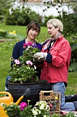 Zwei Frauen beim Bepflanzen von Töpfen im Garten