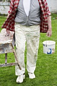 Man carrying painter's bench & paint pot