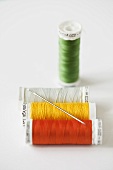 Four different spools of thread and a sewing needle