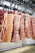 Sides of meat hanging on hooks in a butcher's shop