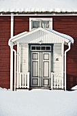 White front door to a wooden house in winter