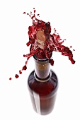 Red wine spraying out of a bottle