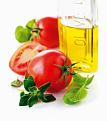 Tomatoes, a bottle of olive oil and fresh herbs (close-up)