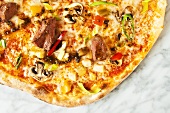 A pizza topped with lamb and vegetables (seen from above)