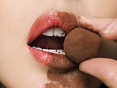 A woman eating a chocolate truffle