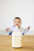Baby-Flasche im Vorder- und Baby im Hintergrund