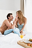 A man feeding his girlfriend in bed