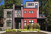Modernes Haus mit Fronten in verschiedenen Farben und Materialien; davor ein frisch angelegter Blumengarten