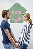 A couple in front of a wall with a house painted on it