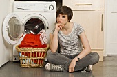 A young woman sitting in front of a washing machine