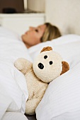 Woman in bed with teddy bear